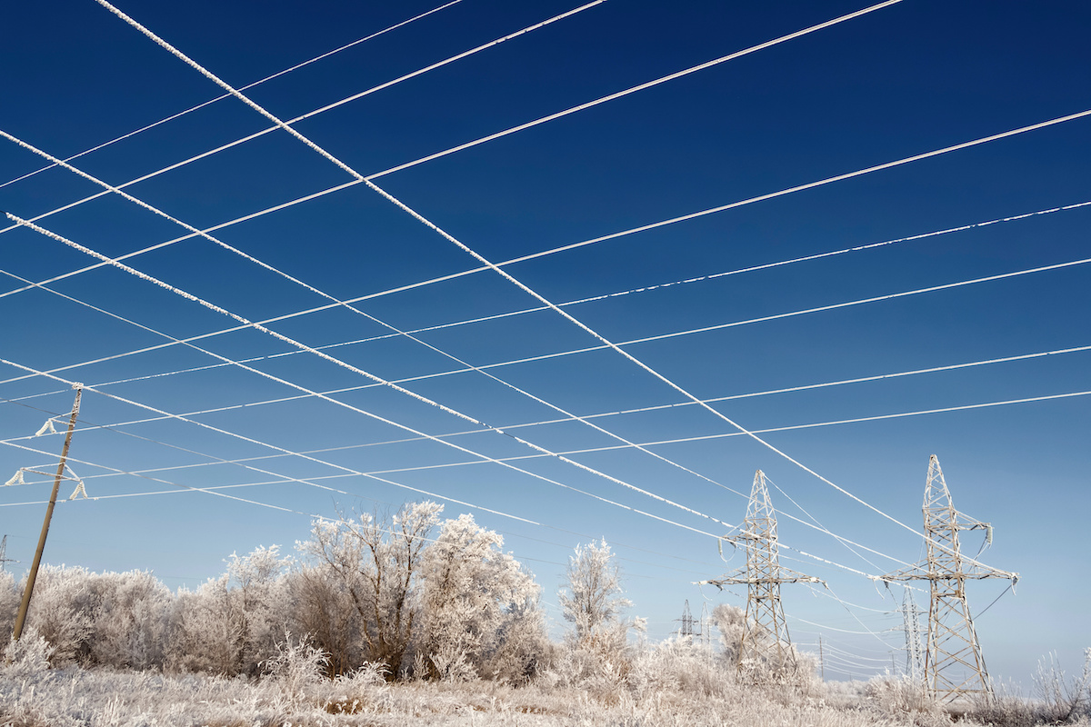 frozen power lines and trees against blue sky